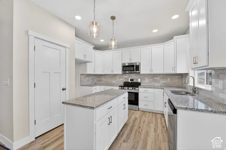 Kitchen featuring white cabinetry, granite countertops, stainless steel appliances, and wood-finish flooring