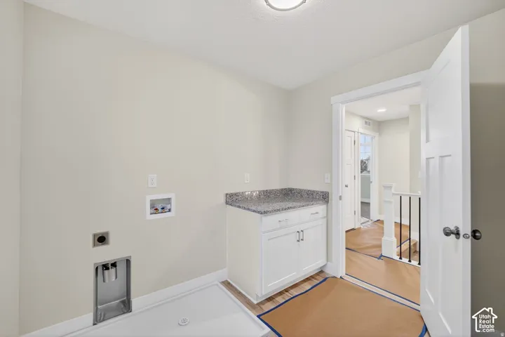 Laundry area featuring a built-in cabinet with a speckled countertop, integrated washing machine hookups, and a utility sink