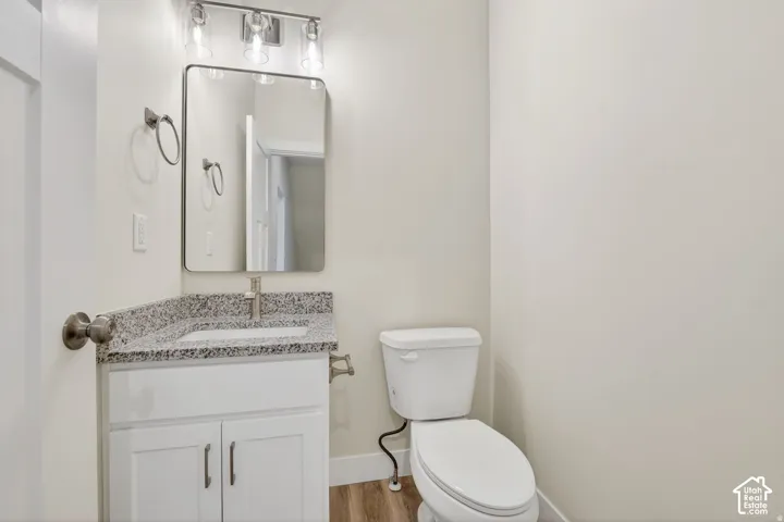 White vanity with a granite countertop, undermount sink, contemporary faucet, and rectangular framed mirror