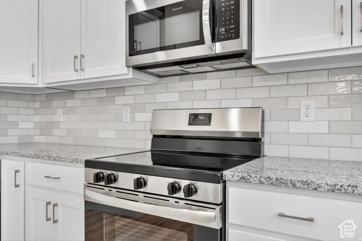 Stainless steel appliance suite, white shaker cabinetry, speckled countertops, and a subway tile backsplash