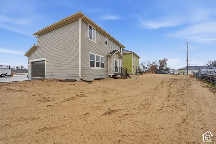 Gray siding exterior with multiple windows, an attached garage, and a rear entry with steps