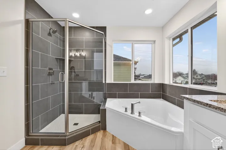Wood-finish flooring with a corner shower featuring dark gray wall tile and a glass enclosure