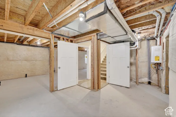 Unfinished lower level with exposed ceiling joists, concrete flooring, and multiple doorways