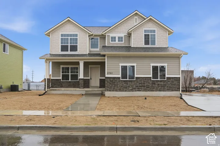 Two-story exterior with horizontal siding and shake accents, stone veneer foundation, covered front porch, multiple gables, and an attached driveway