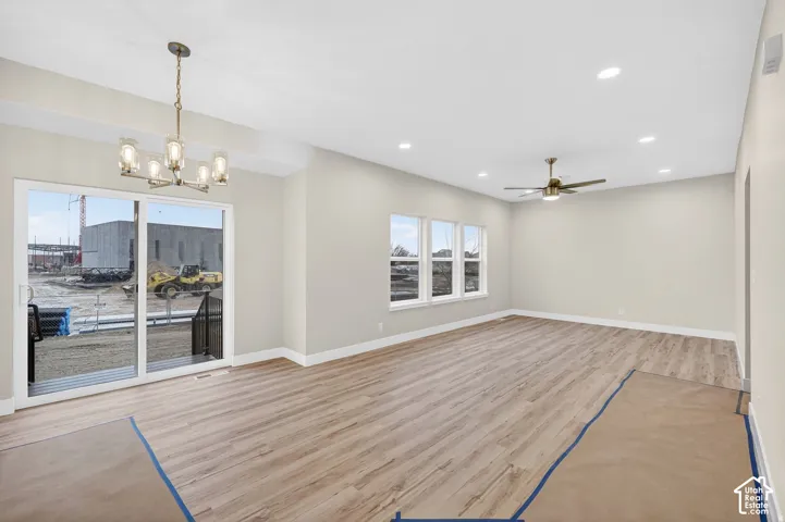 Spacious room featuring wood-finish flooring, multiple windows, a sliding glass door, a ceiling fan, and recessed lighting