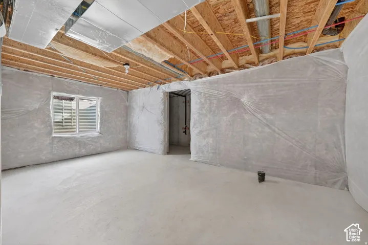 Concrete flooring, exposed ceiling joists, plastic-covered walls, and a single window