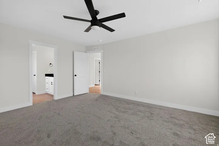 Neutral wall paint, gray carpet flooring, black ceiling fan, white interior doors, and white trim