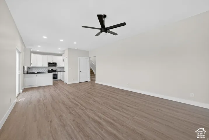 Open-concept living area with wood-finish flooring, recessed lighting, and a modern ceiling fan