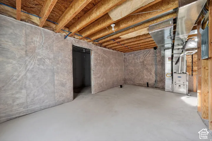 Unfinished basement with concrete flooring, exposed wood joists, and installed insulation