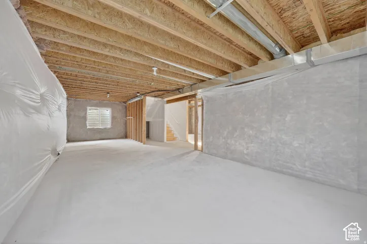 Unfinished basement with open wood joist ceiling, concrete flooring, and exposed ductwork