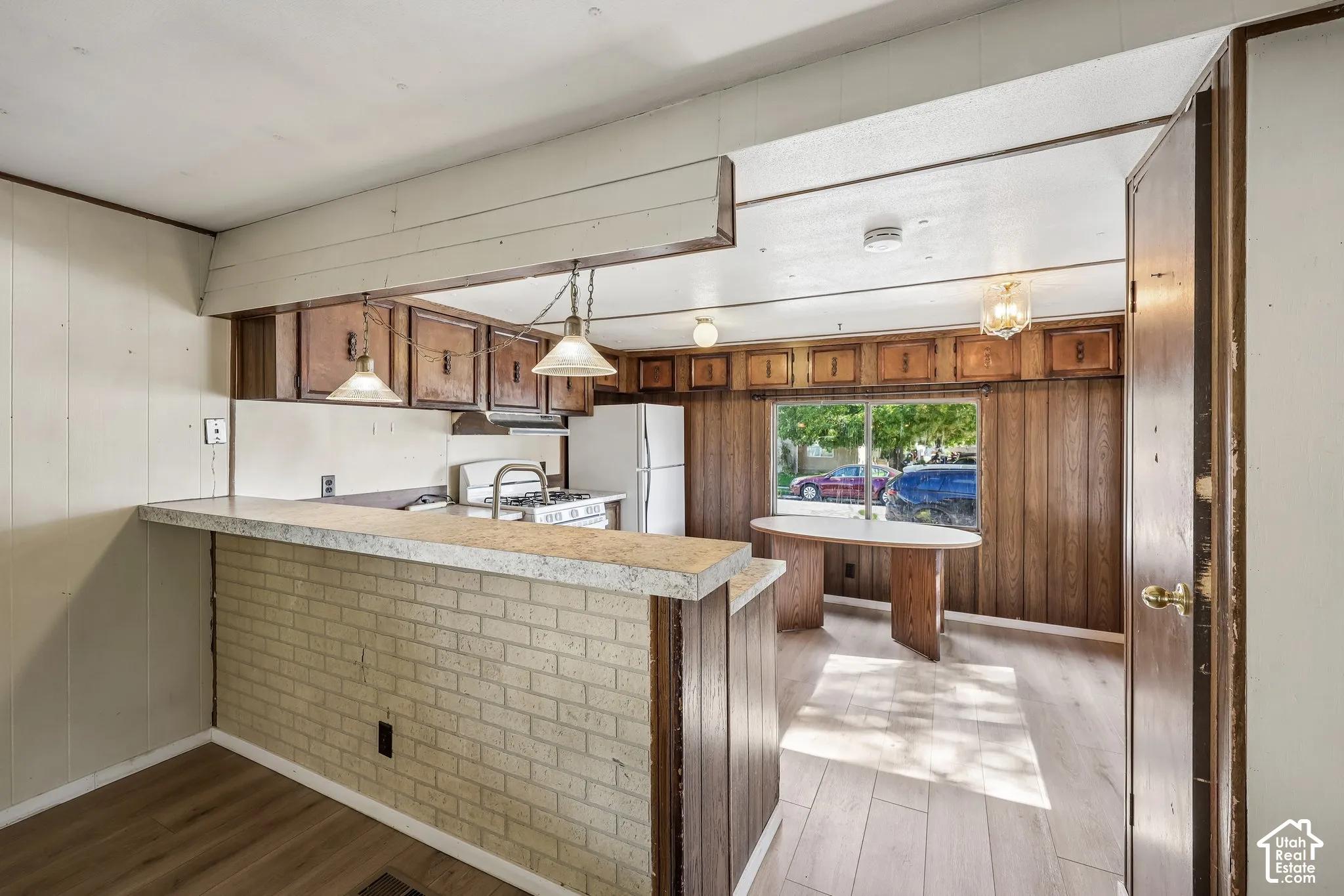 Kitchen with wood-finish flooring, a breakfast bar with a brick base, and overhead pendant lighting