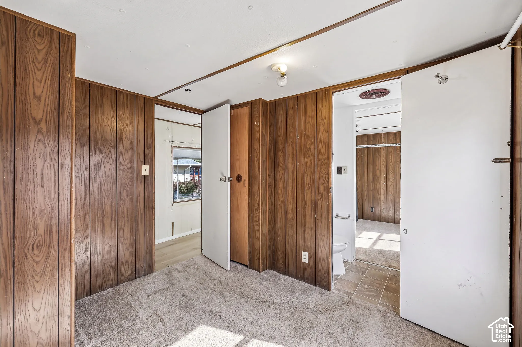 Wood-finish wall paneling, carpeted flooring, and a white interior door
