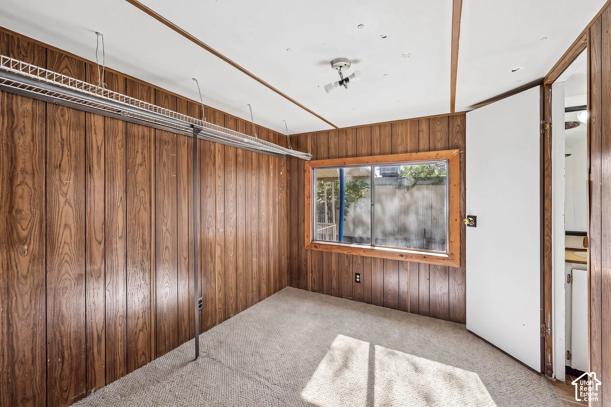 Wood-panel walls, carpeted flooring, and a large window with wood trim