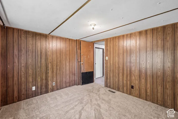 Carpeted interior space with wood-paneling walls and a flush-mounted ceiling light fixture