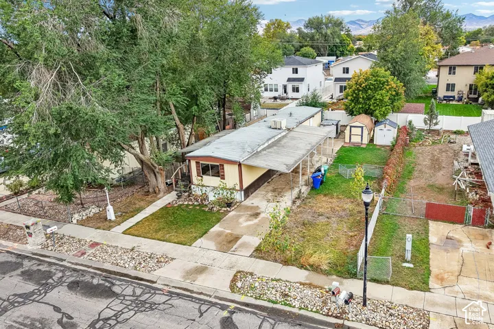 Extended driveway, fenced perimeter, multiple storage sheds, and mature landscaping