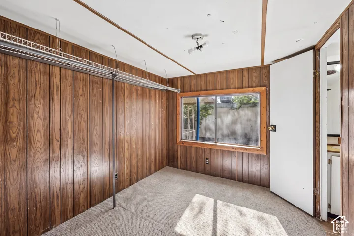 Wood-panel walls, carpeted flooring, and a large window with wood trim