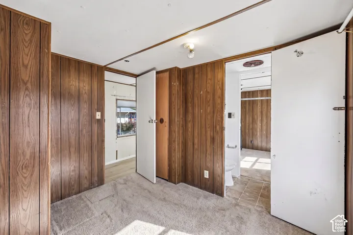 Wood-finish wall paneling, carpeted flooring, and a white interior door
