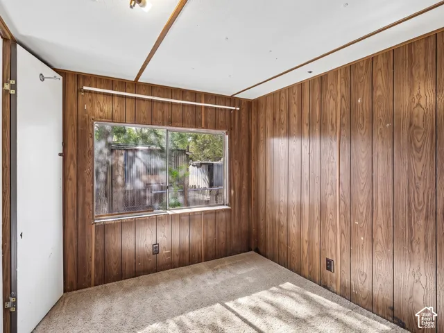 Carpeted room featuring wood-finish wall paneling, a large window, and a ceiling-mounted light fixture