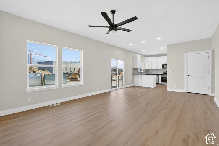 Open-concept living space with wood-finish flooring, recessed lighting, and a modern ceiling fan