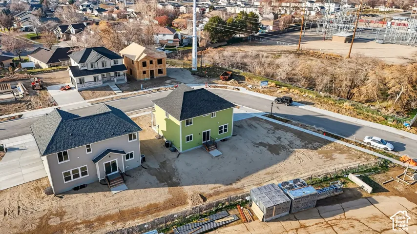 Recently constructed residence featuring a gray exterior, dark shingle roof, concrete driveway, and front door with glass paneling