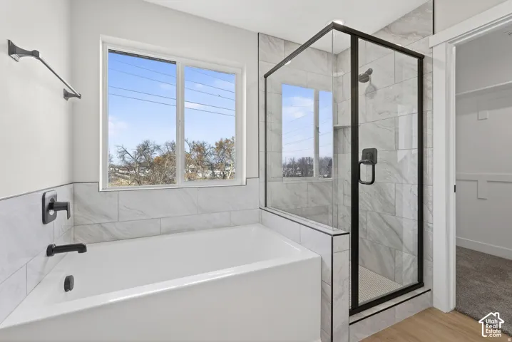 Bathtub with matte black fixtures, tile surround, and a window
