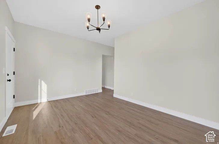 Wood-finish flooring, neutral wall tones, white trim, and a modern four-light chandelier