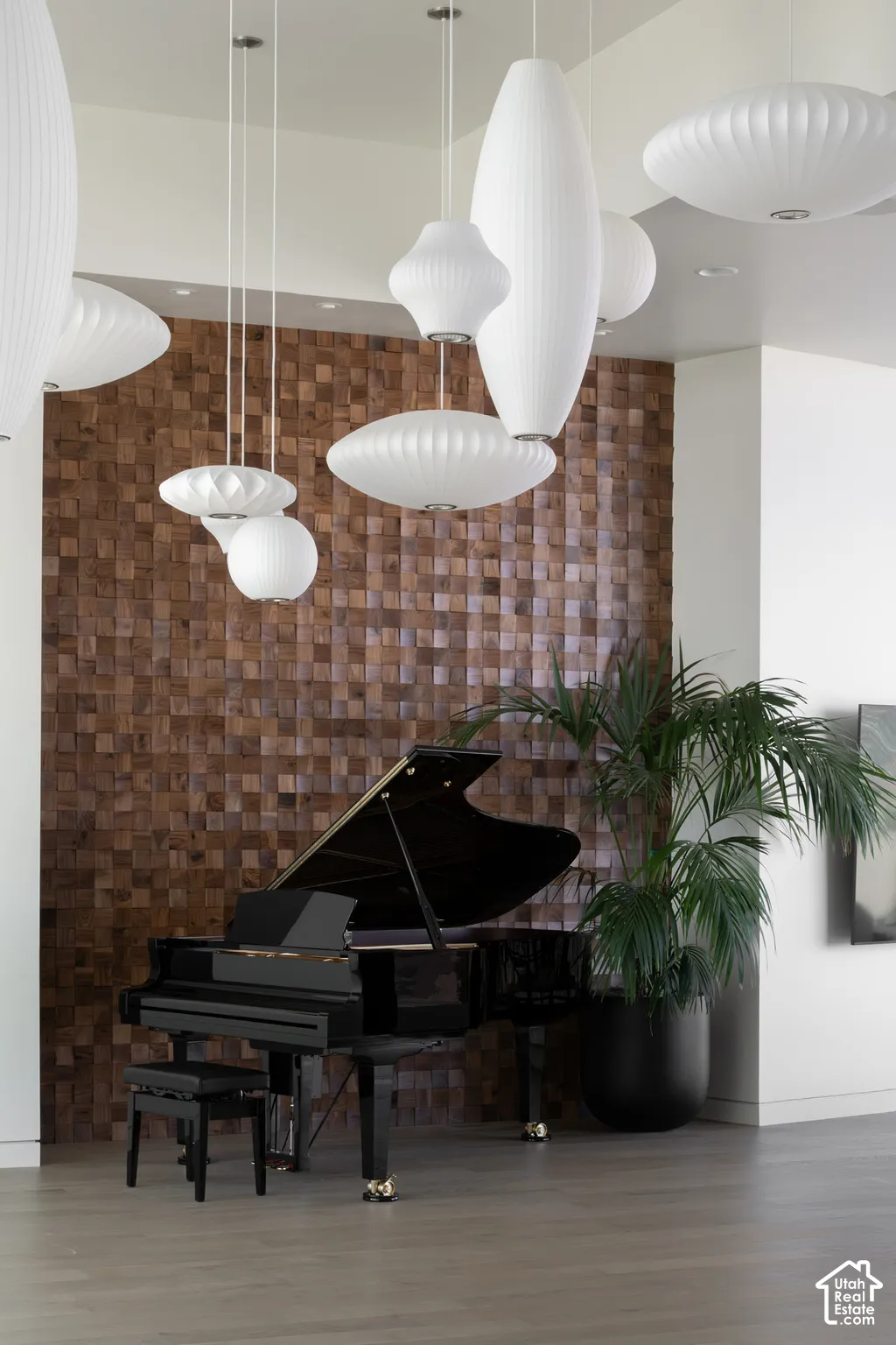 Wood-finish flooring, accent wall with wood block detailing, and multiple pendant light fixtures