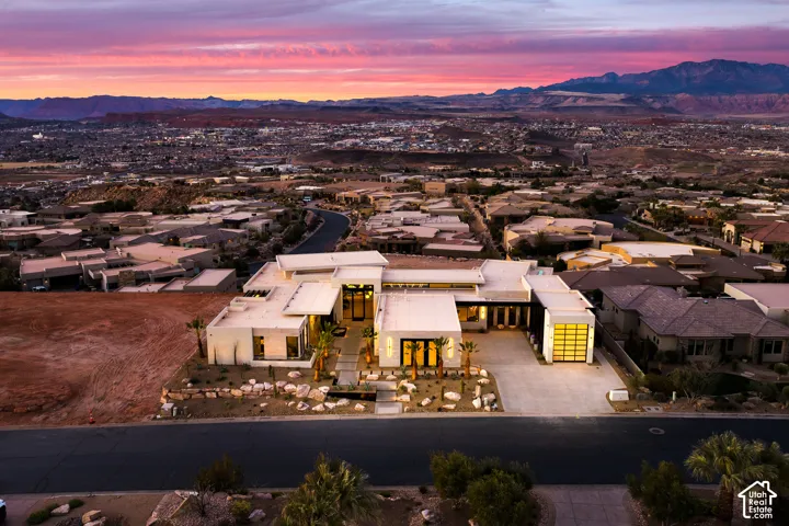 Modern architecture with an expansive driveway, a translucent garage door, arid landscaping, and a surrounding mountainous landscape