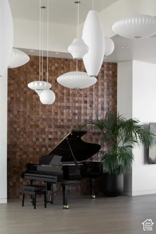 Wood-finish flooring, accent wall with wood block detailing, and multiple pendant light fixtures