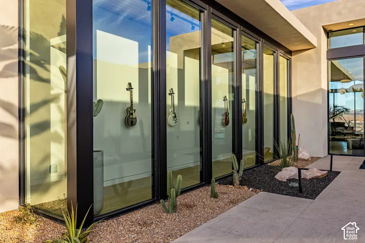 Expansive floor-to-ceiling windows with black frames, concrete exterior, and a desert landscape with gravel and natural rock elements