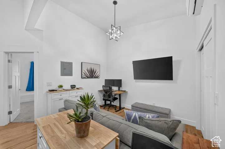 Vaulted ceilings, wood-finish flooring, modern pendant lighting, white shaker-style cabinetry, and a split system air conditioning unit