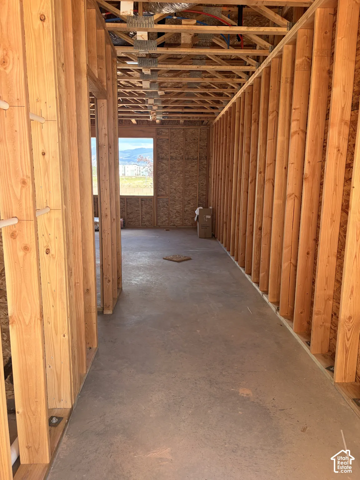 New construction framing with exposed ceiling joists, concrete flooring, and a window providing natural light