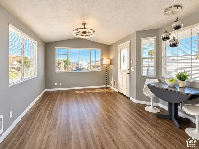 Interior space featuring wood-finish flooring, multi-pane windows, vaulted ceilings, a contemporary semi-flush mount ceiling fan, and a three-light pendant fixture