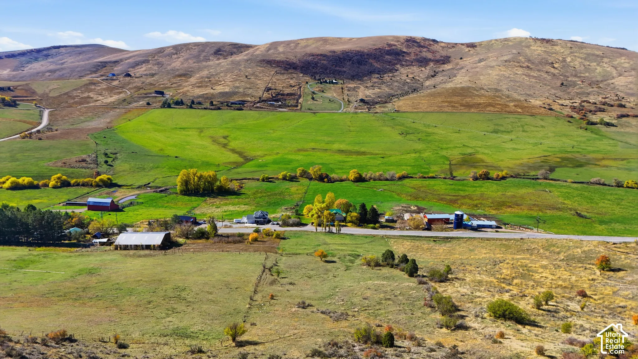Expansive acreage featuring rolling terrain, open meadows, mature trees, and a mountain backdrop