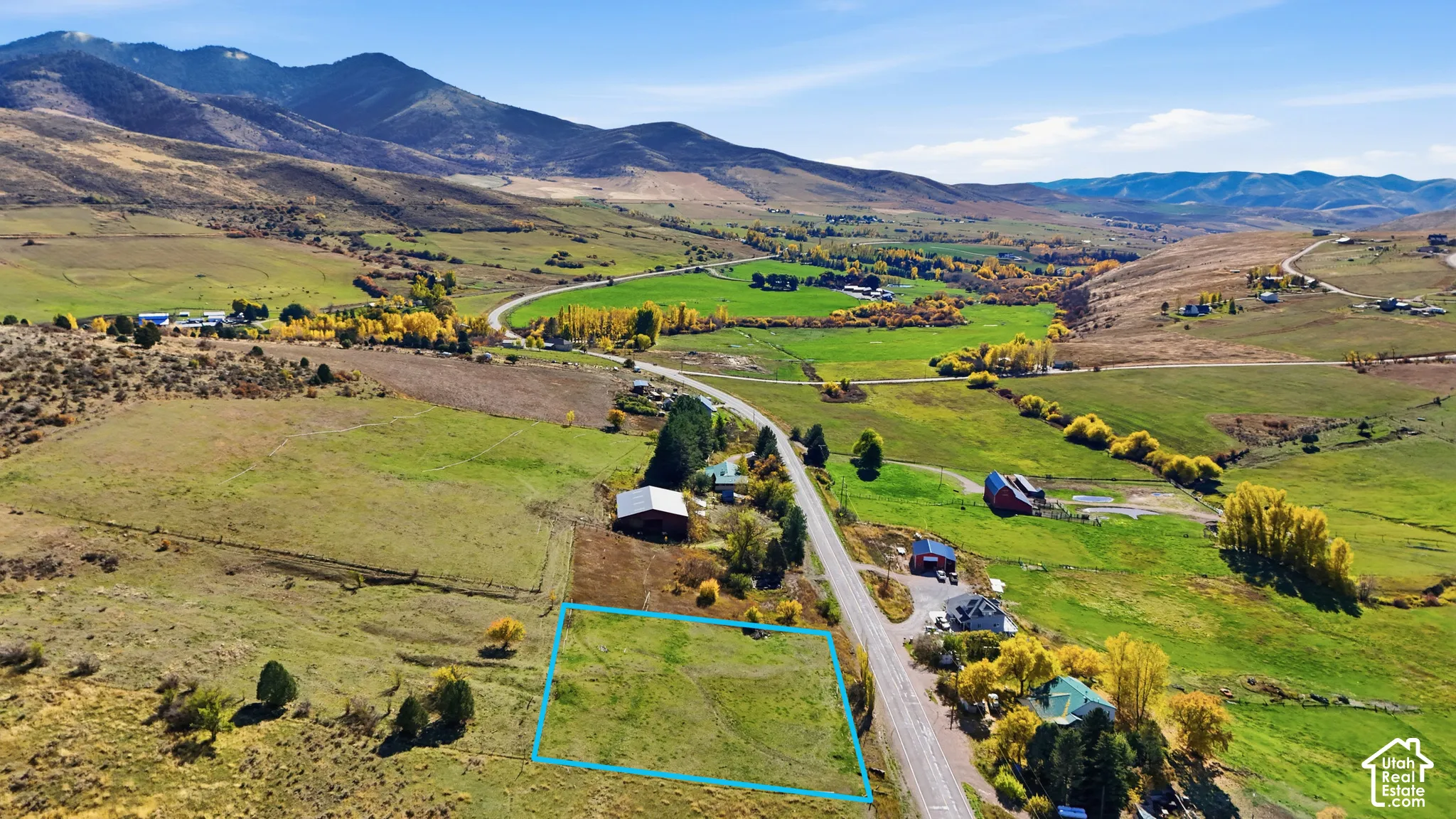 Expansive plot of land featuring rolling terrain, direct access to a paved road, and mountainous scenery