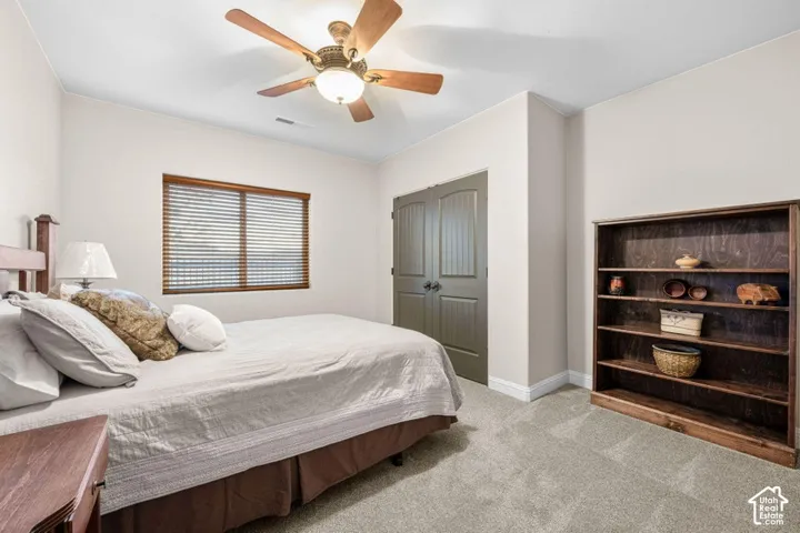 Wood-framed window with blinds, ceiling fan with integrated lighting, wood-finish bi-fold doors, and a built-in wood bookshelf