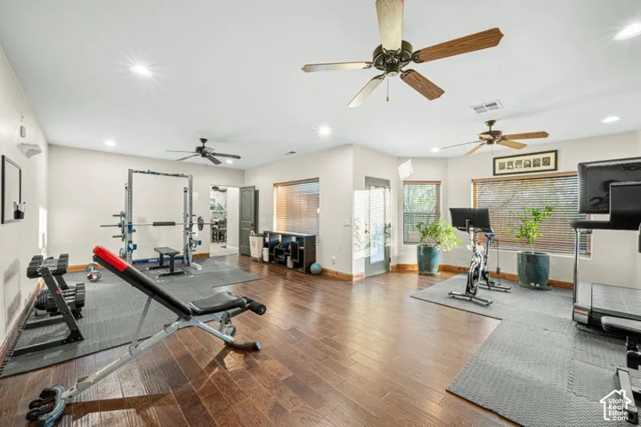 Spacious interior room with wood-finish flooring, recessed lighting, and multiple ceiling fans