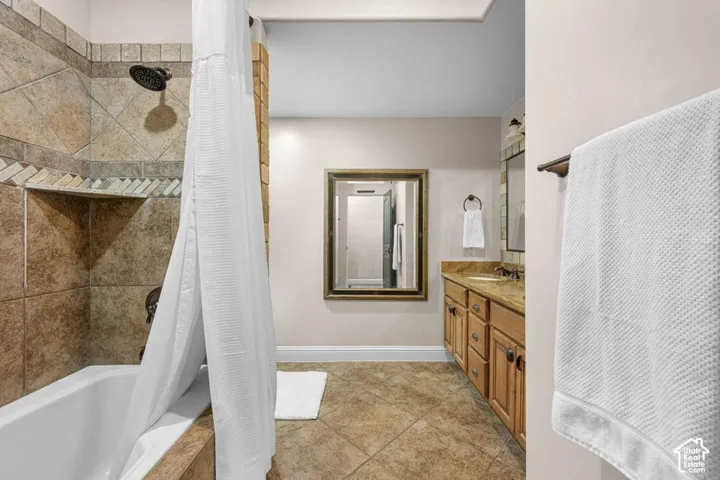 Tiled tub and shower combination with an integrated shelf, dual vanity with wood cabinetry, and a full-width mirror
