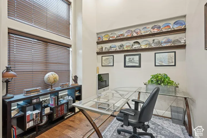 High ceilings with stacked windows featuring custom wood blinds, wood-finish flooring, and built-in shelving