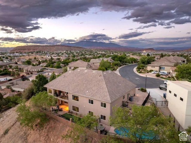 Two-story stucco exterior with multiple windows, covered balcony, ground-level patio, and built-in swimming pool