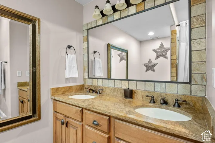 Dual vanity with stone-finish countertop, wood-finish cabinetry, and oil-rubbed bronze fixtures