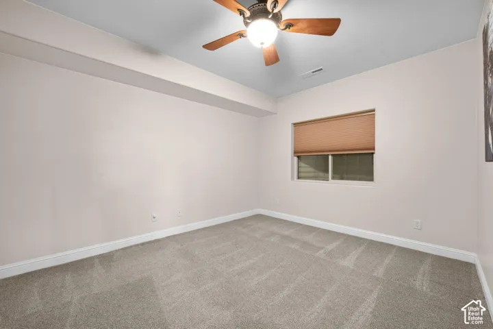 Recessed window with cellular shade, overhead ceiling fan with light, and light-toned carpeting