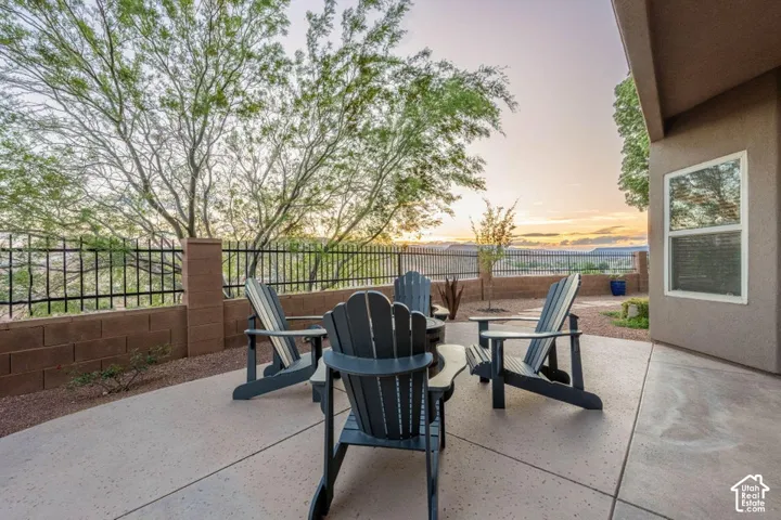 Stucco exterior with a large picture window, concrete patio, and a stone retaining wall