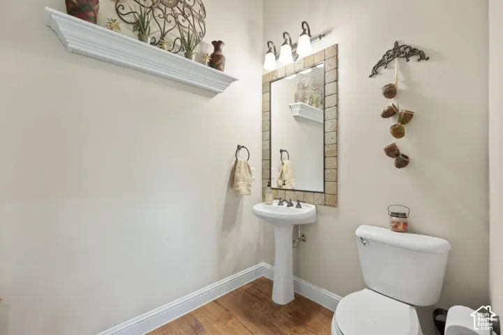 White pedestal sink with a chrome faucet, framed mirror, and a three-light vanity fixture