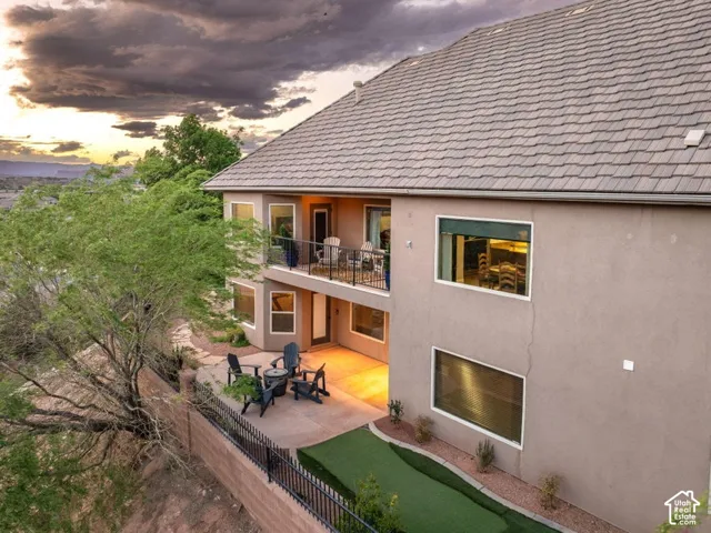 Multi-level exterior featuring a private balcony, lower-level patio, and tile roof