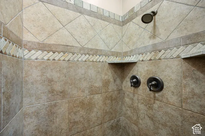 Tiled shower enclosure featuring a diamond pattern accent band, decorative herringbone tile inlay, and integrated corner shelves