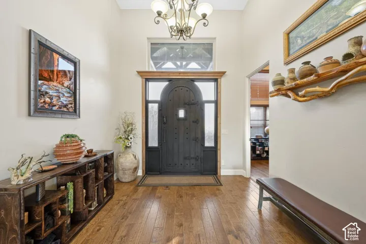 Arched entry door with sidelights and transom window, wood-finish flooring, high ceilings, and a decorative chandelier