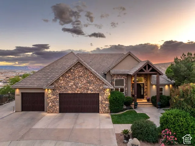 Stucco and stone exterior with a covered entry, multiple gables, and a concrete driveway