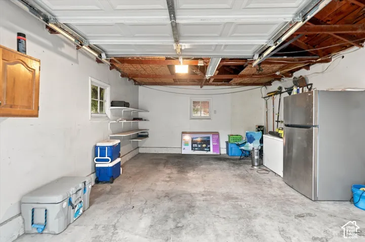 Garage interior featuring concrete flooring, built-in wooden wall cabinetry, and multiple fixed shelving units