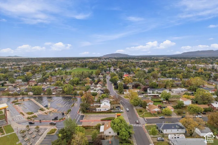 Aerial perspective of the property surroundings featuring mature trees, paved local roadways, and a mountainous horizon